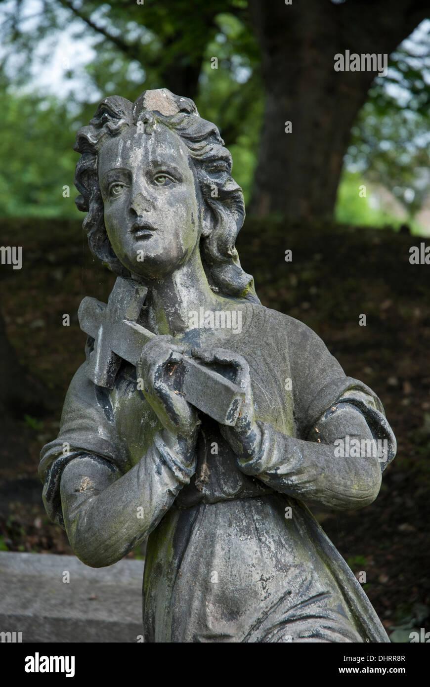 Weathered and damaged statue depicting a woman holding a cross, part of a monument in North Merchiston Burial Ground, Edinburgh. Stock Photo