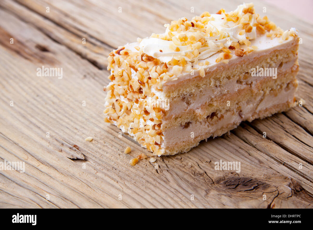 Piece of creamy hazelnut cake on old wooden table Stock Photo