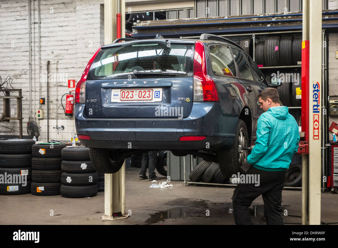 Car mechanic changing summer tyres and mounting winter tires on wheels