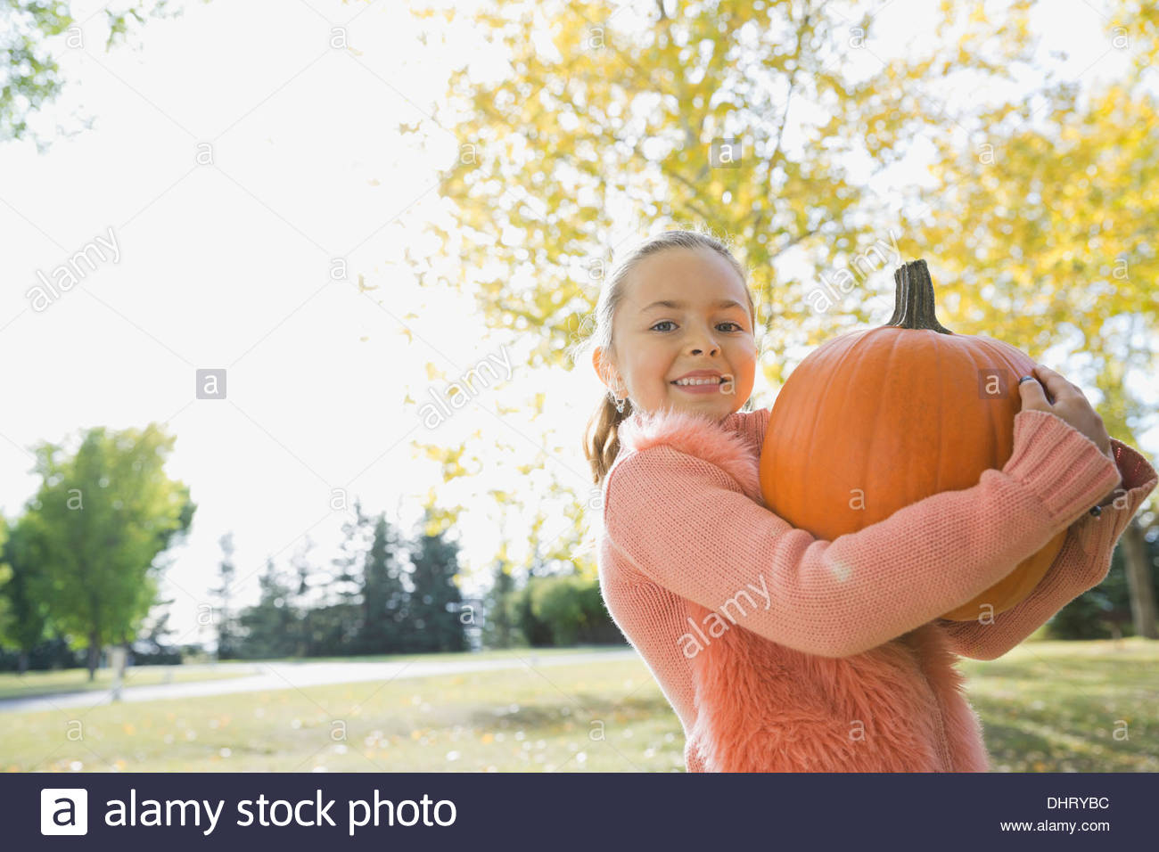 Portrait of happy girl carrying pumpkin Stock Photo