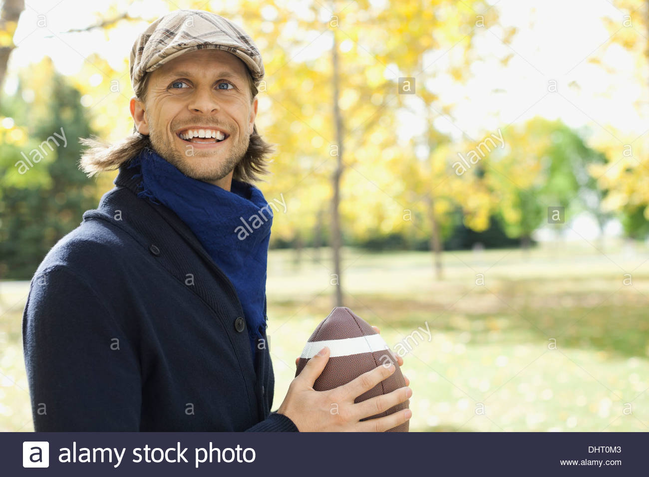 Happy mid adult man playing American football at park Stock Photo