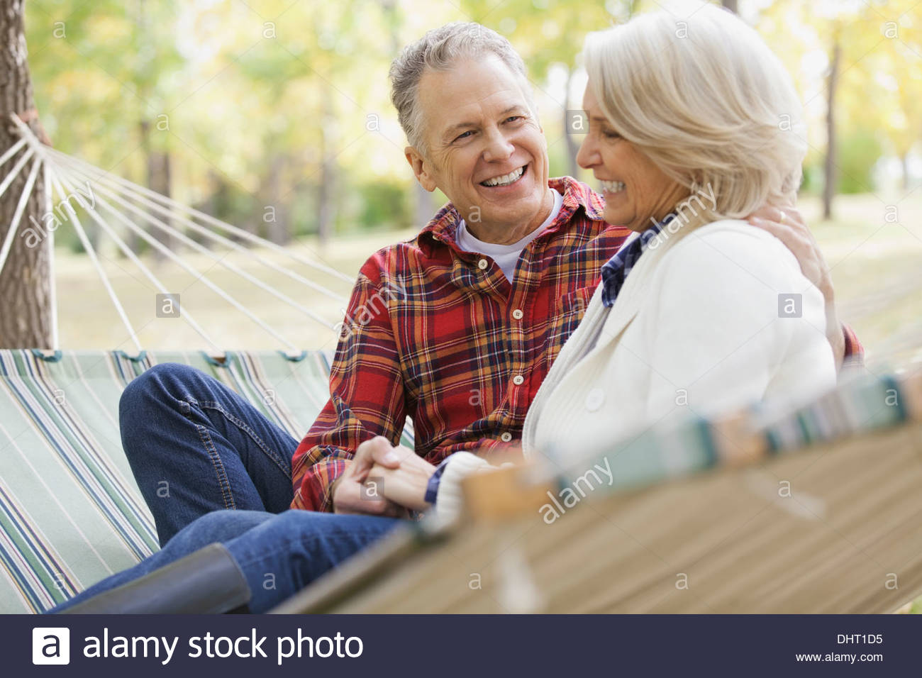 Loving mature couple sitting in hammock at park Stock Photo