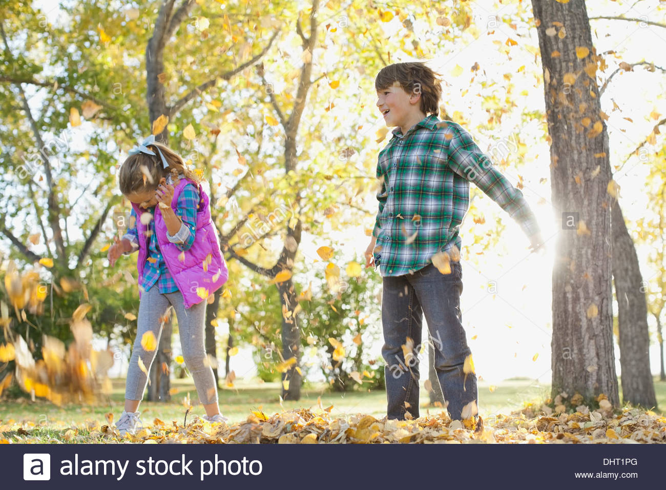 Full length of happy children playing with autumn leaves in park Stock Photo