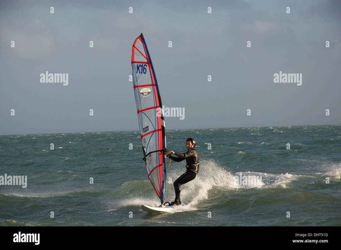 Water sports. Windsurfing man, wearing a wetsuit, speeding over the