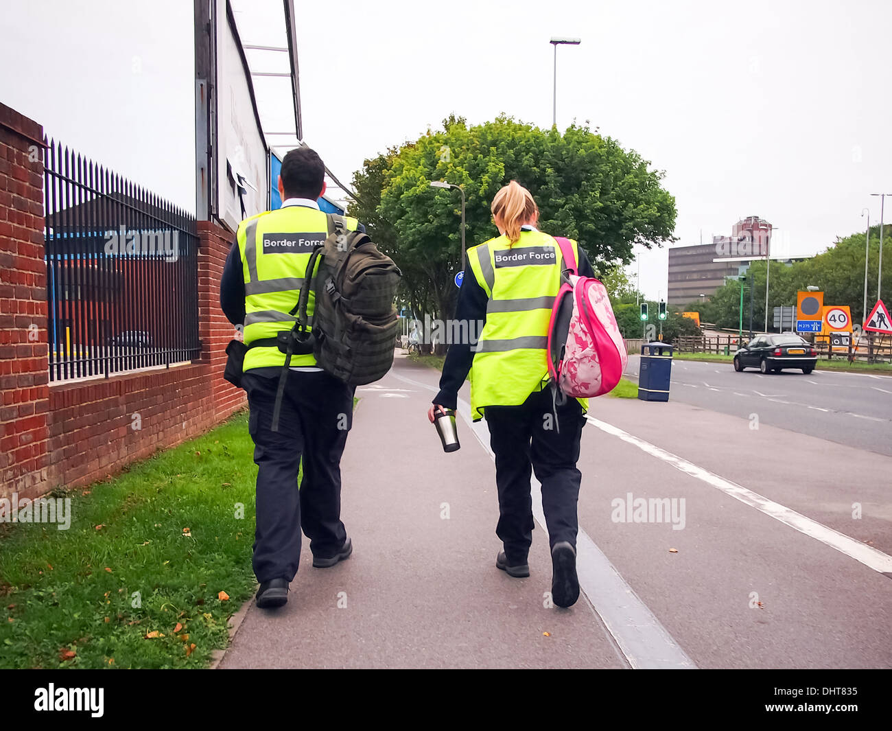 Members of the UK Border Force walking to work carrying personal bags and cups. Stock Photo