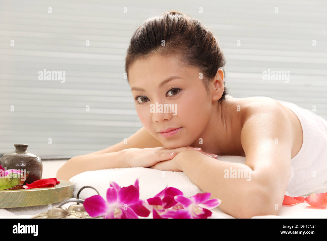 East Asian Woman Lying On Bed Decorated With Flowers Doing Spa Stock