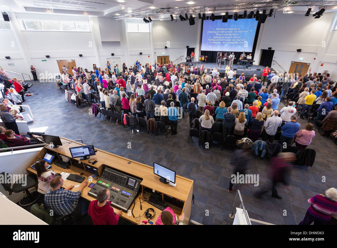 The audio visual control kiosk and congregation participating in contemporary worship music during Sunday Service inside the large modern Kings Community Church. Stock Photo