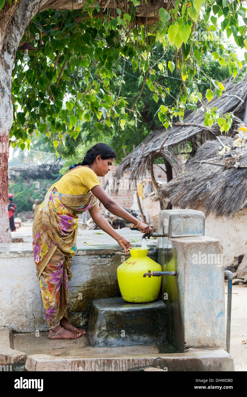 Indian woman filling a plastic pot with water from a standpipe in a rural Indian village street. Andhra Pradesh, India Stock Photo