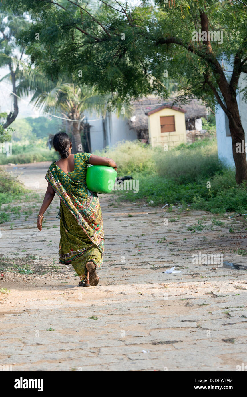 Indian woman carrying a plastic pot with water from a hand pump in a rural Indian village. Andhra Pradesh, India Stock Photo