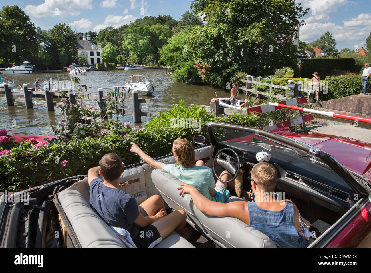 Netherlands, Loenen aan de Vecht. River Vecht. Boys in old fashioned car looking at yachts in the river Stock Photo