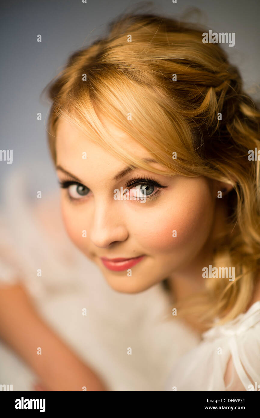 Fairytale theme image of a young blonde woman female teenage girl wearing a white dress Stock Photo