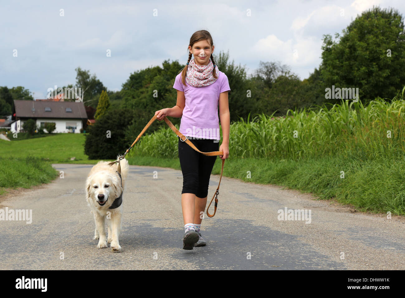 Little girl taking a dog for a walk outdoors in nature Stock Photo