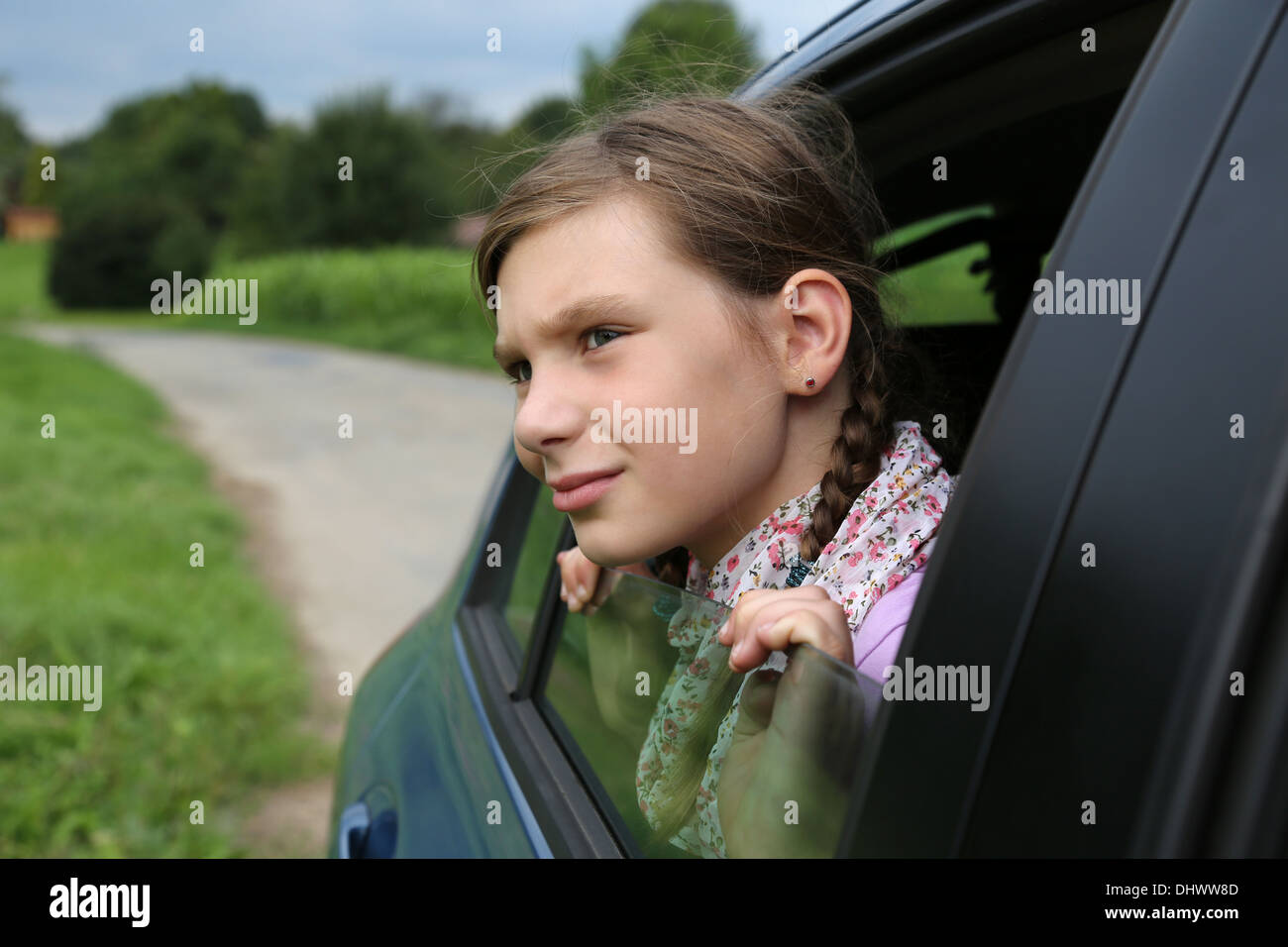 Little girl looking out of the window of a car while driving Stock Photo