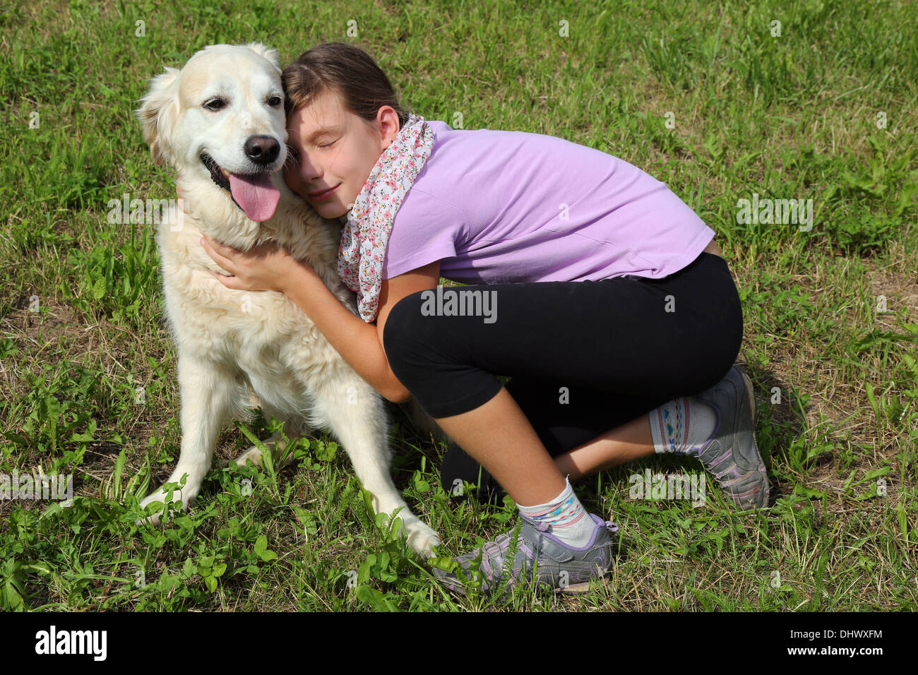 Little girl caressing her pet dog on a meadow Stock Photo