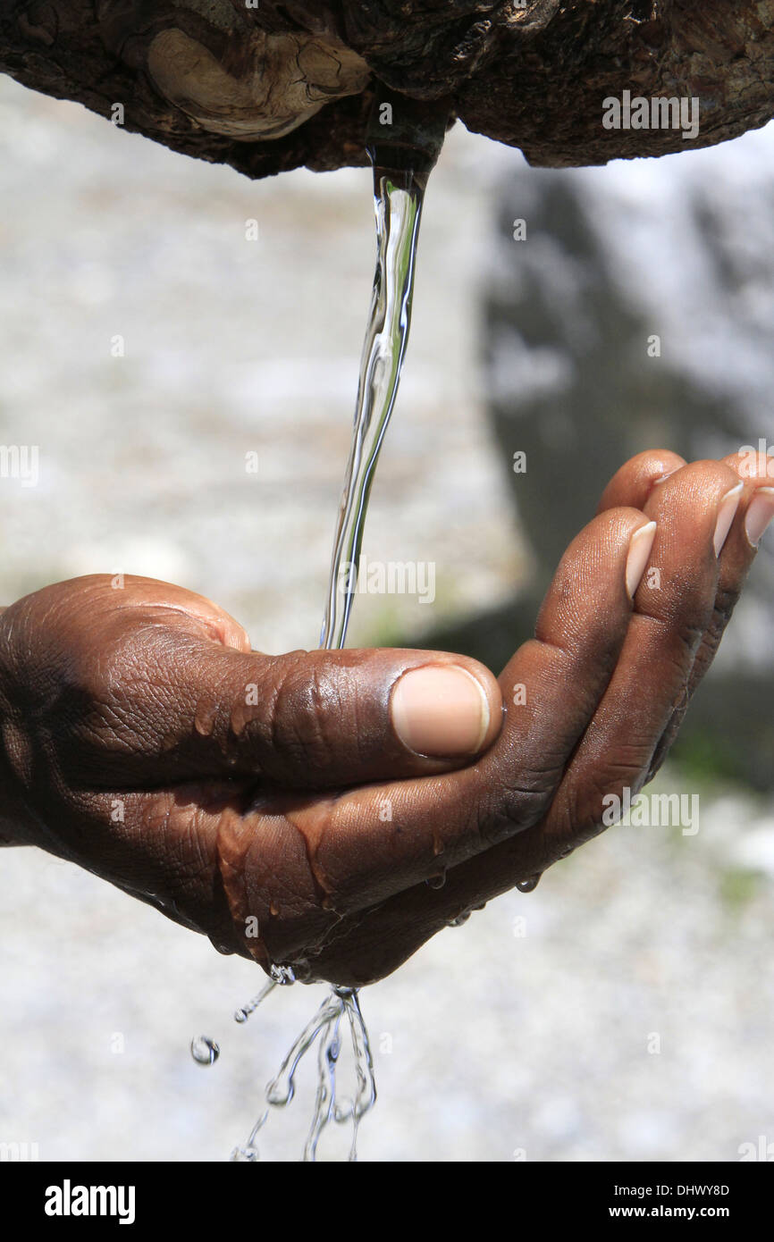 Water flowing from a fountain in the hand of an African. Stock Photo