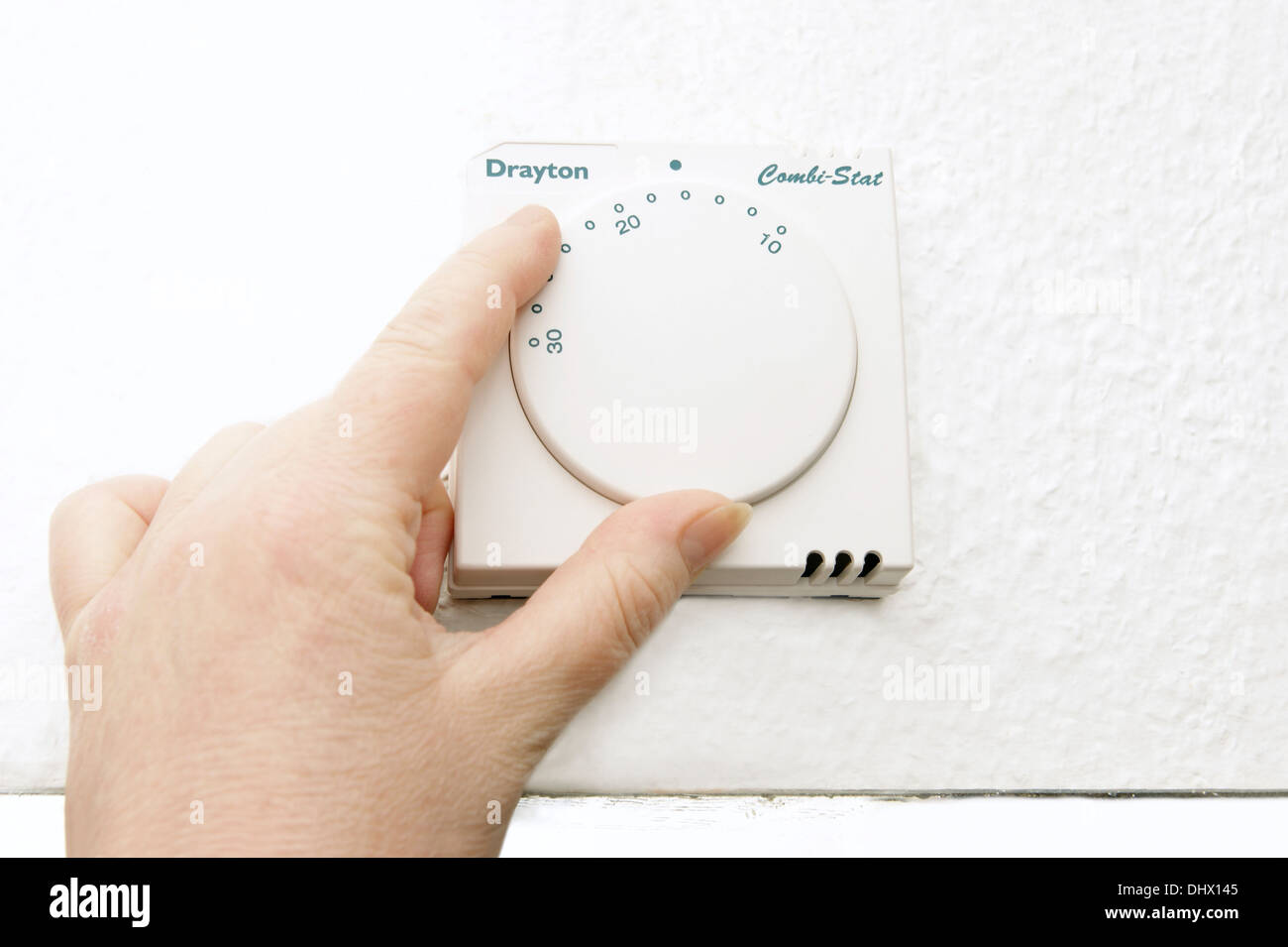 Energy efficiency - woman lowering the thermostat on the central heating control to combat global warming and climate change Stock Photo