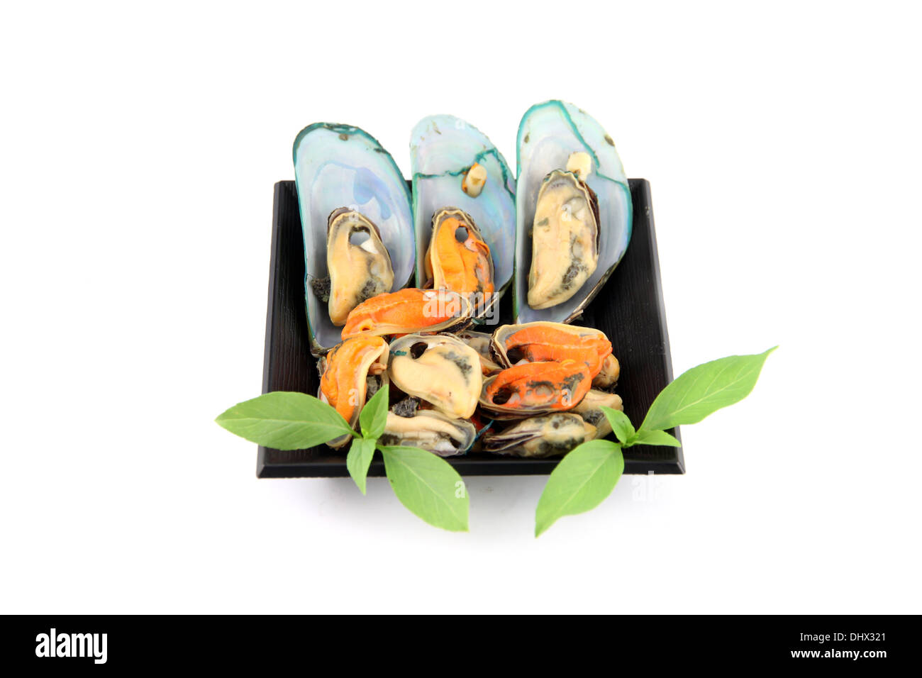 Mussels on black dish and vegetables in dish as well on white background. Stock Photo