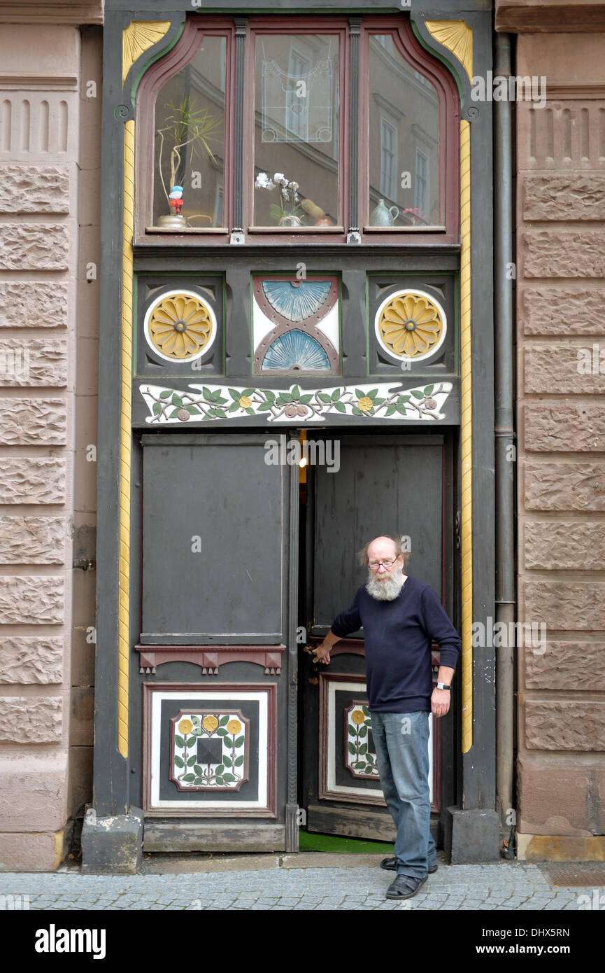 Eisenach, Germany. 07th Nov, 2013. Klaus Trippstein, resident and owner of the 'Narrow House', poses in front of his house in Eisenach, Germany, 07 November 2013. With a width of 2.05 meters, it is probably the smallest inhabited half-timbered house in Germany. Klaus Trippstein's research has shown that the house is over 250 years old. Klaus Trippstein had bought the house in the mid-seventies and restored it piece by piece. The house hosts a small exhibition of paintings, sculptures and historic furnishings. Photo: Marc Tirl/dpa/Alamy Live News Stock Photo
