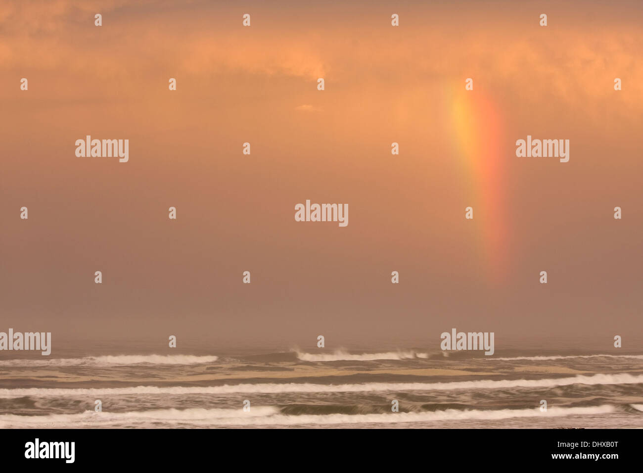 A rainbow forms over the Pacific Ocean at sunrise near Tillicum Beach ...