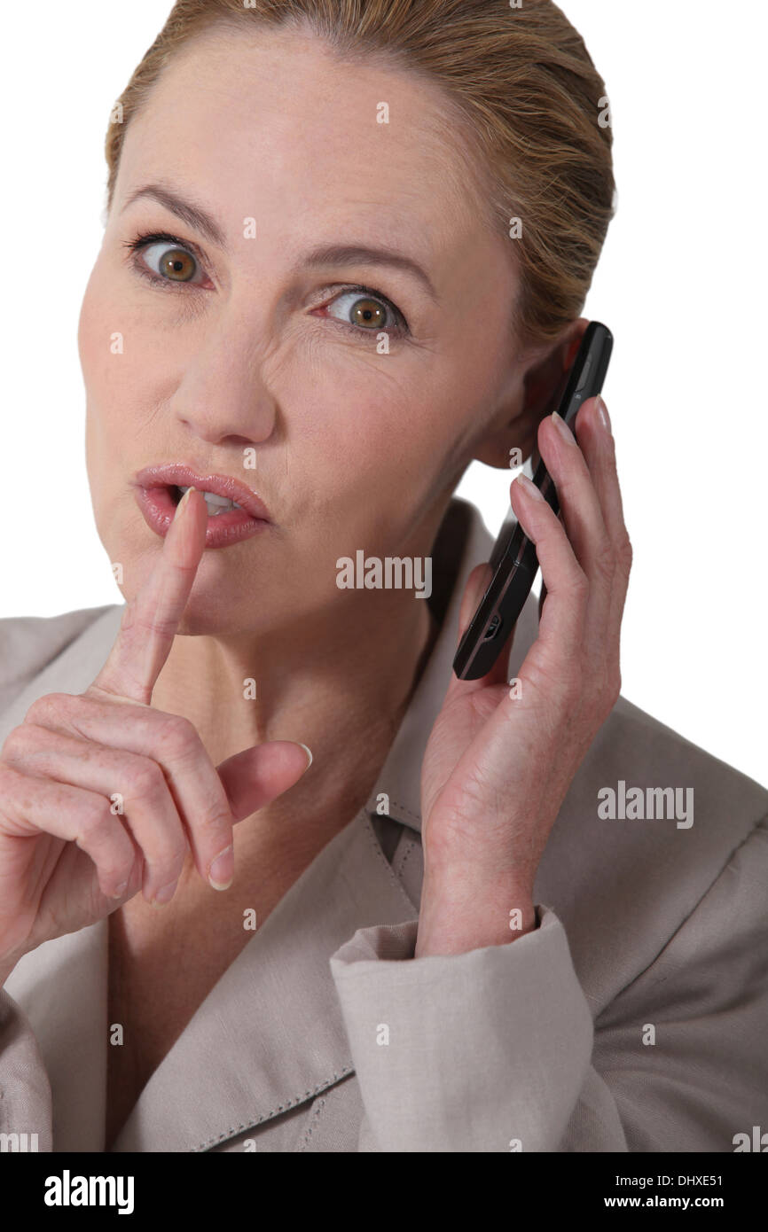 Woman indicating quiet whilst holding a phone Stock Photo