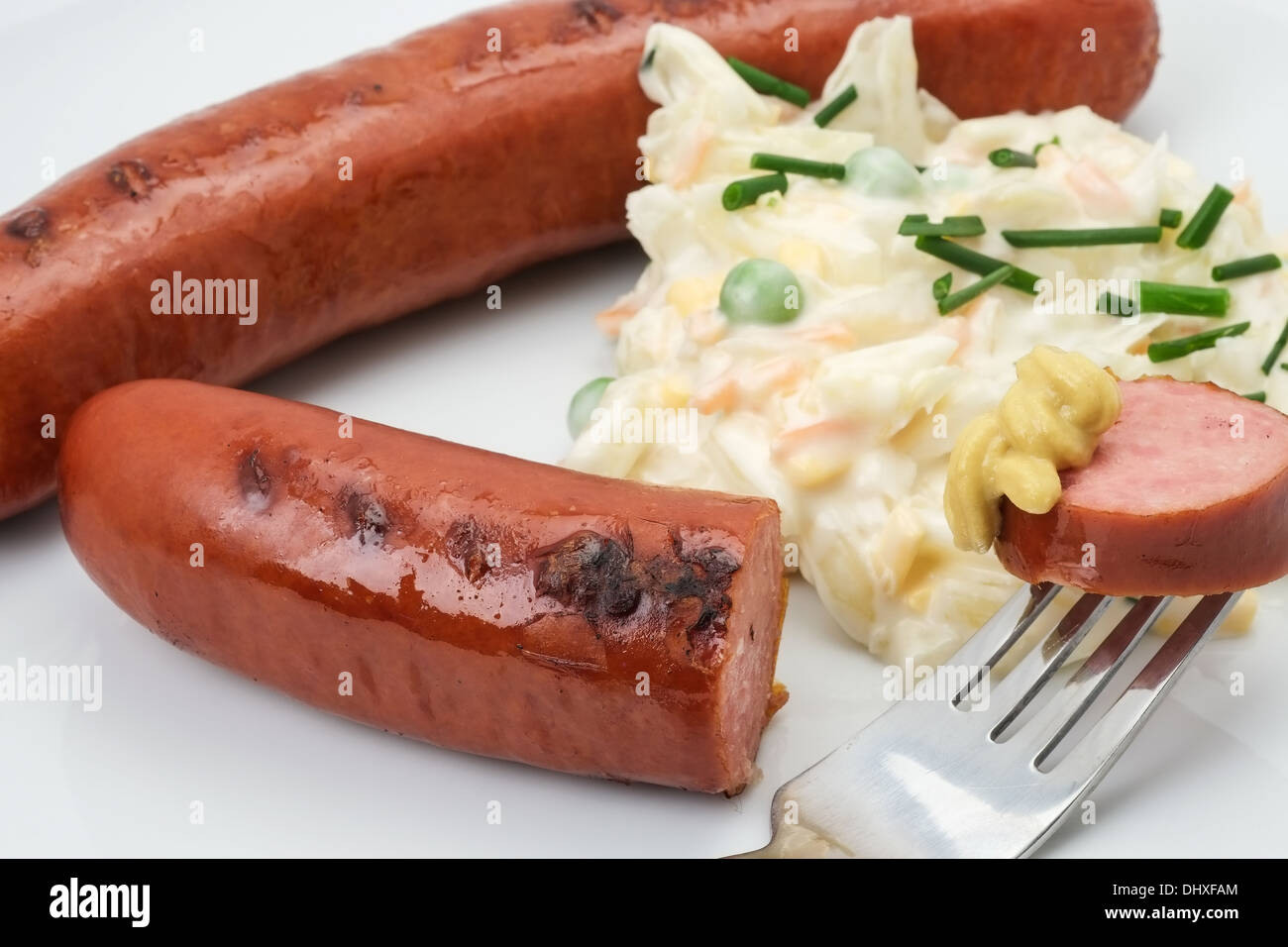 Close-up of a ready to eat German Bratwurst sausage served with coleslaw and mustard. Stock Photo