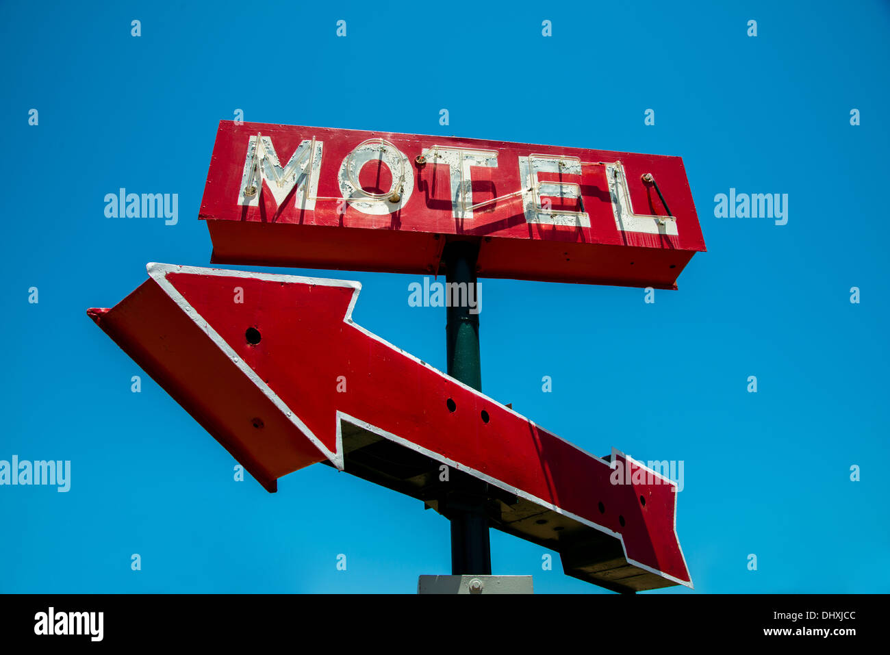 A vintage red neon hotel sign with a red arrow and a sky blue background Stock Photo