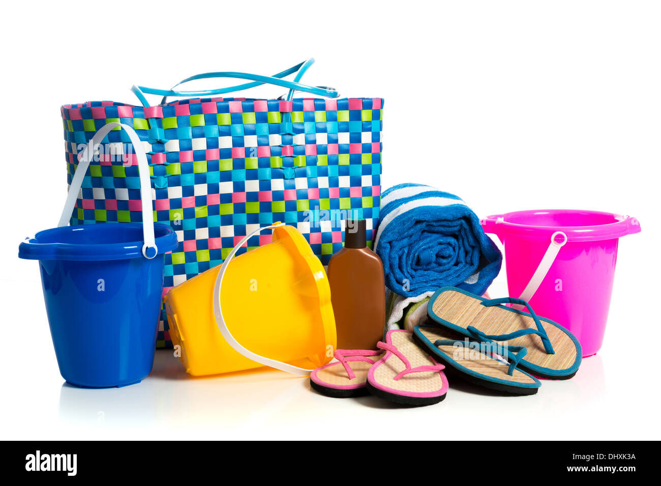 Beach bag with buckets, towel, flipflops and suntan lotion on a white