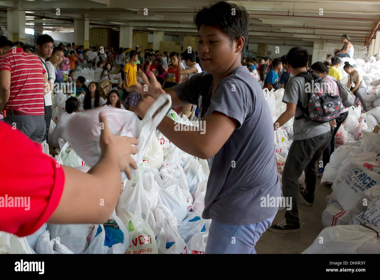 International Convention Centre,Cebu City 16/11/2013. A Cebu City initiative involving a number of Government Agencies in the aftermath of Typhoon Haiyan/Yolanda. A 24hr relief aid operation involves the receiving and re-packing of food items destined for the hardest hit areas. Volunteers are mainly students. Relief packs contain 6 kilos of rice,5 tins of sardines,5 tins of corned beef/beef loaf. Stock Photo