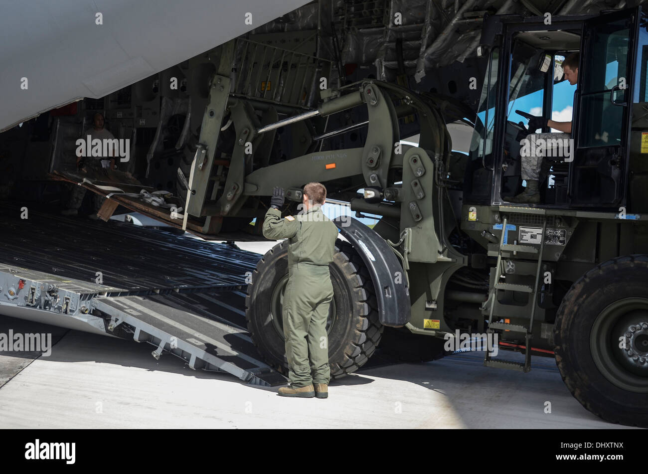Senior Airman Dylan Porras, 535th Airlift Squadron C-17 Globemaster III loadmaster, guides Senior Airmen Christopher Follett, 36th MRS air transportation specialist, in loading a forklift into a C-17 Nov. 15, 2013, on the Andersen Air Force Base, Guam, fl Stock Photo