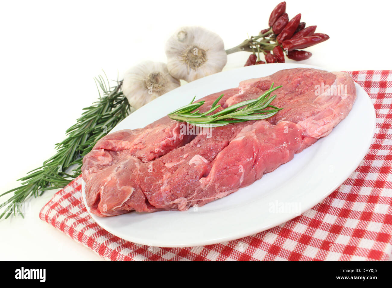 a piece of raw sirloin steak with rosemary and garlic Stock Photo