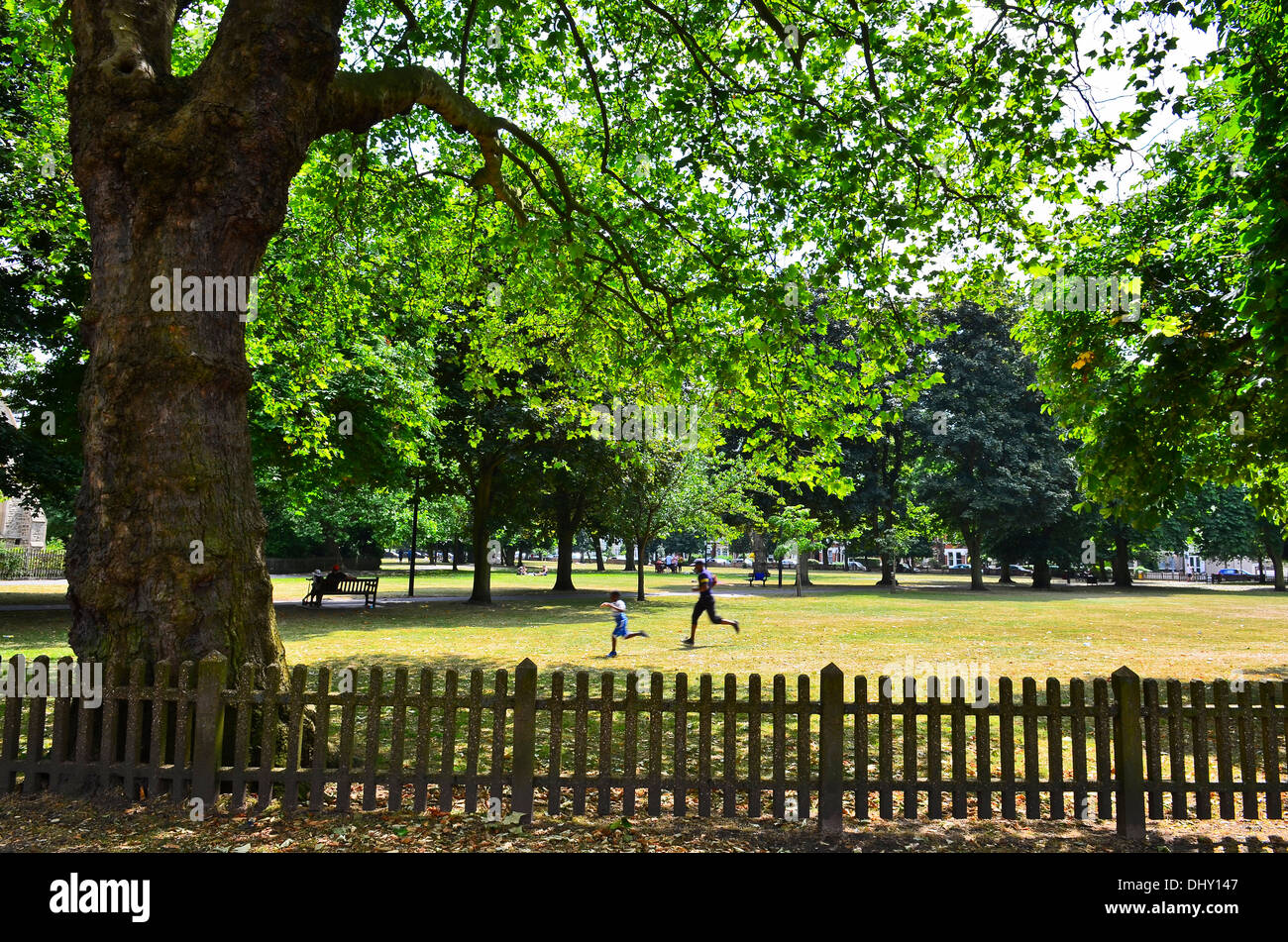 Man and boy running in the sun, summertime, on Christchurch Green, Wanstead, London Stock Photo