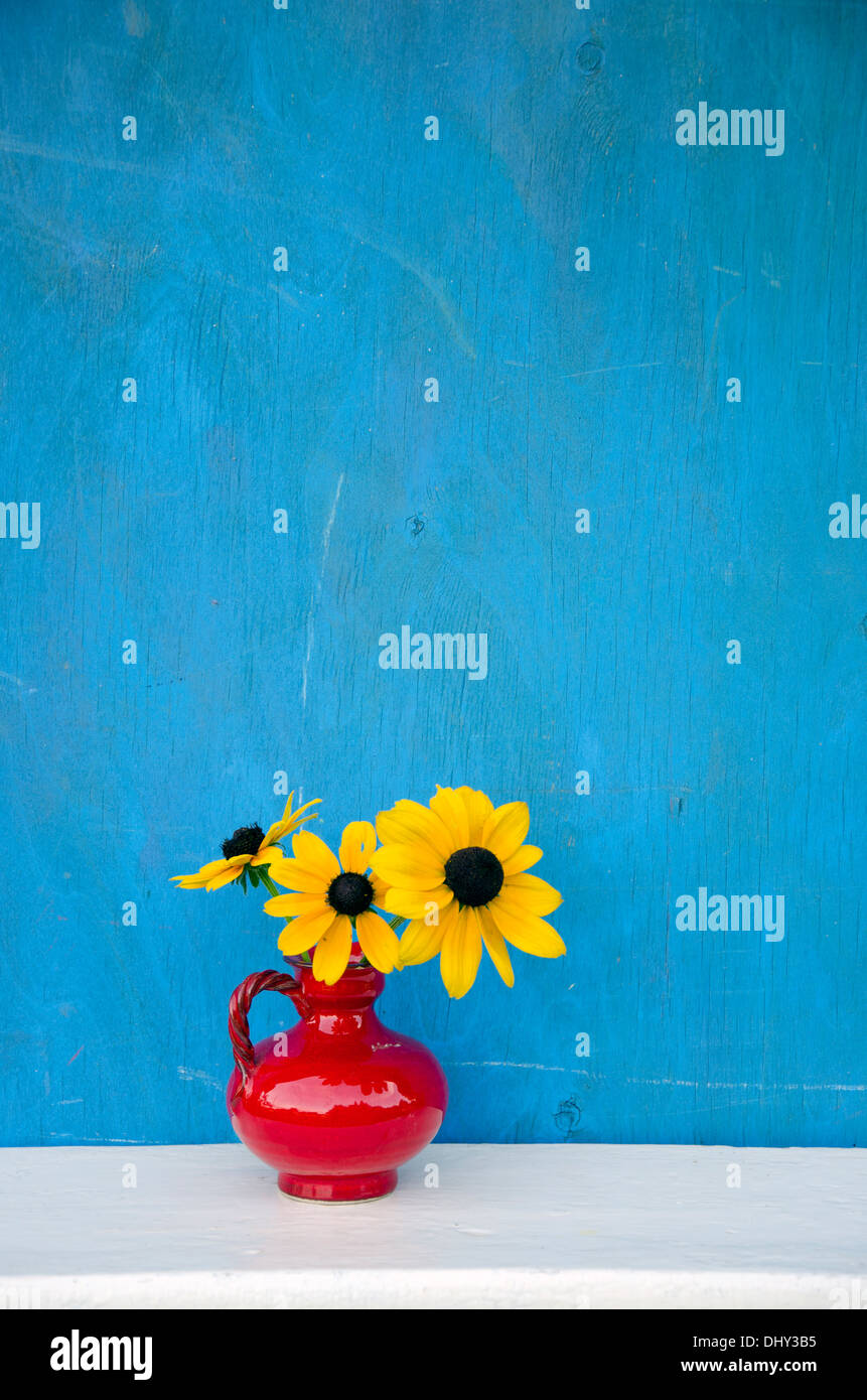 beautiful red vase with yellow flowers on blue background Stock Photo