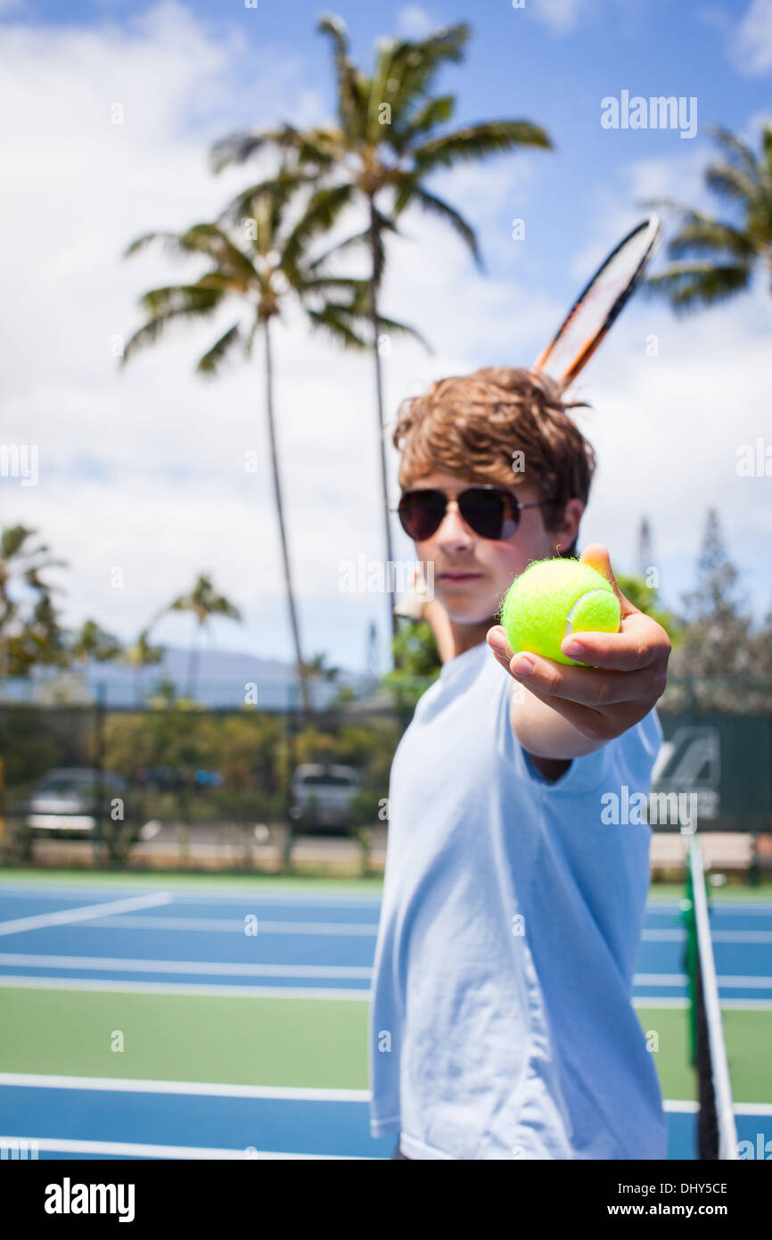 A Handsome Teenager offers the Tennis Ball to viewer while in Hawaii Stock Photo