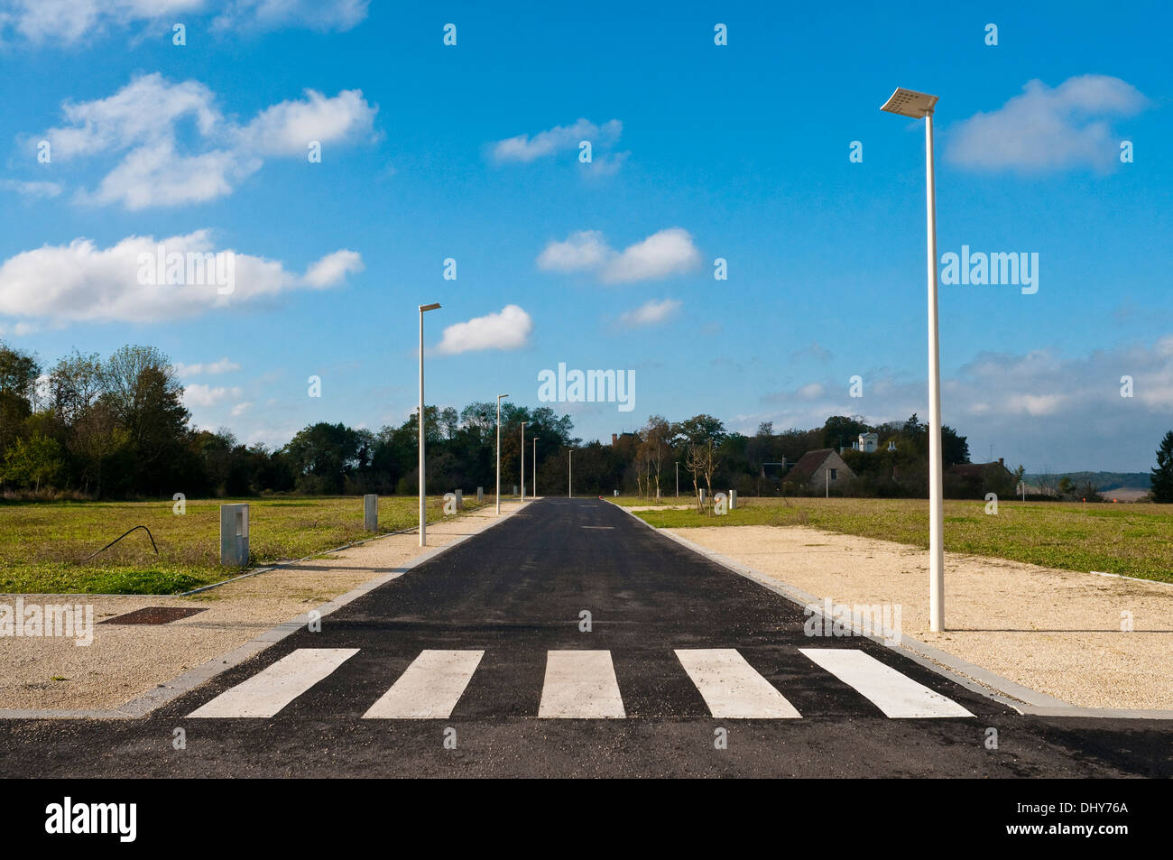 Pedestrian crossing painted on new road through unbuilt housing estate site - France. Stock Photo