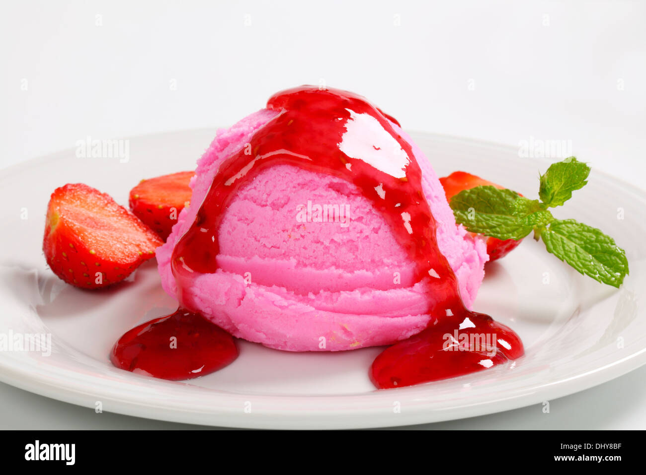 Scoop of pink ice cream with strawberry sauce Stock Photo