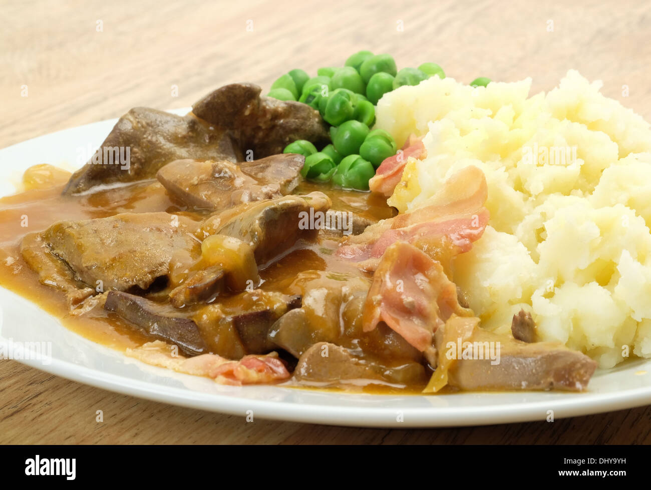 Classic British dinner of liver and bacon served with mashed potato, peas and onion gravy - studio shot Stock Photo