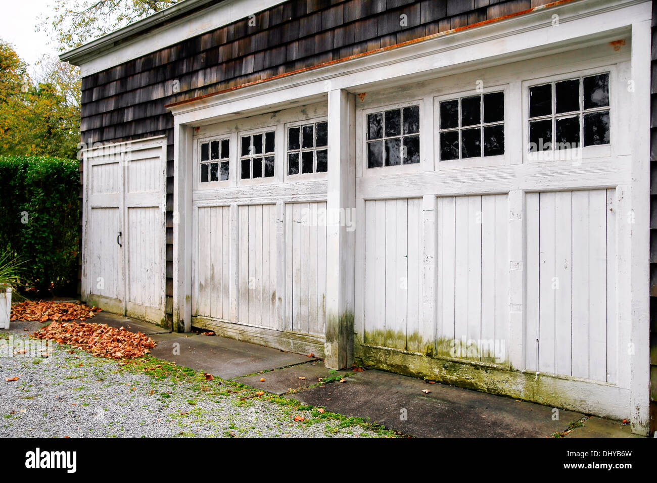 Weather beaten old garage doors, sloppily painted around the window panes. Stock Photo