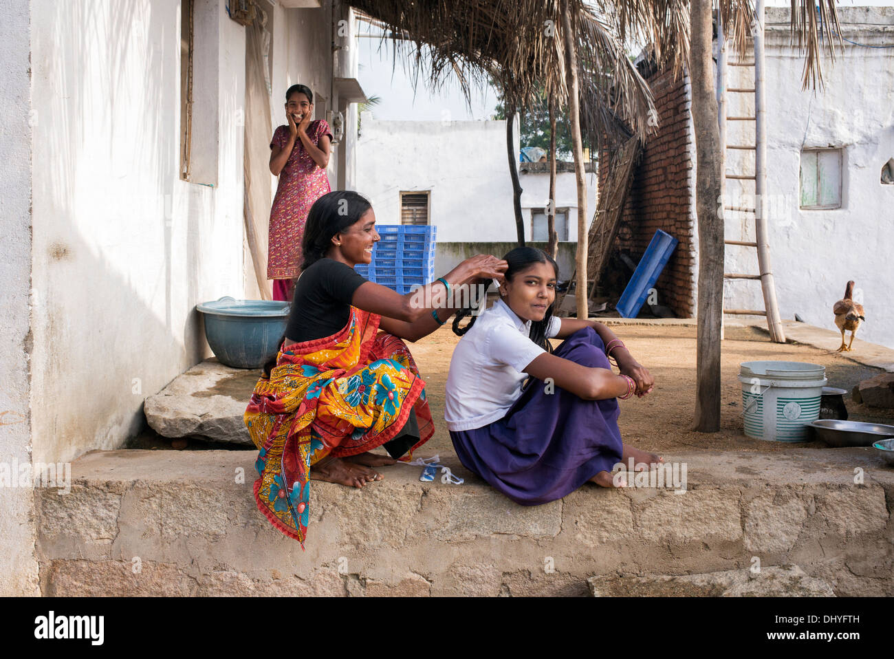 Indian mother plaiting her daughters hair for school in a rural Indian village. Andhra Pradesh, India Stock Photo