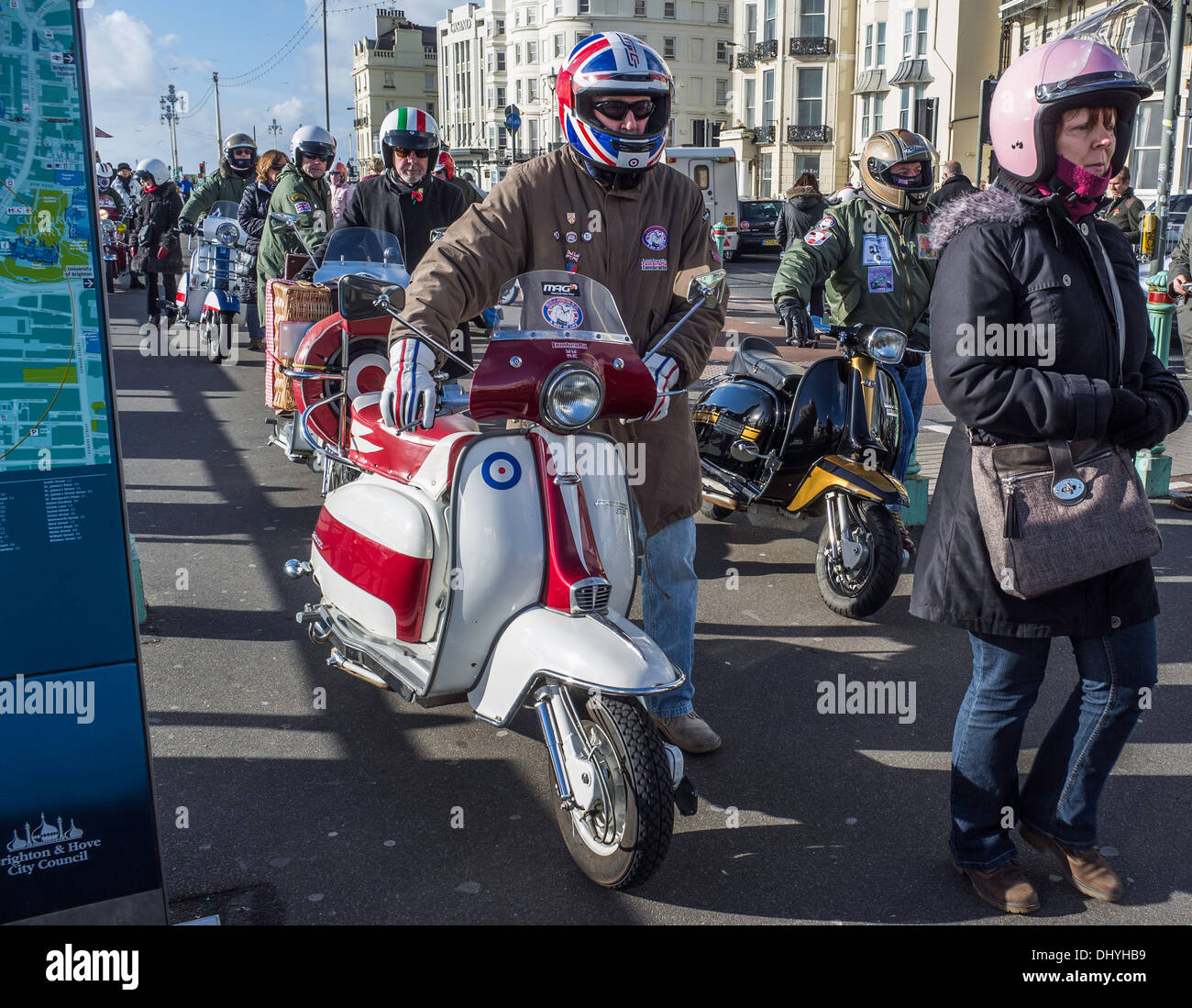Members of a motor scooter club pushing their Lambrettas to a parking