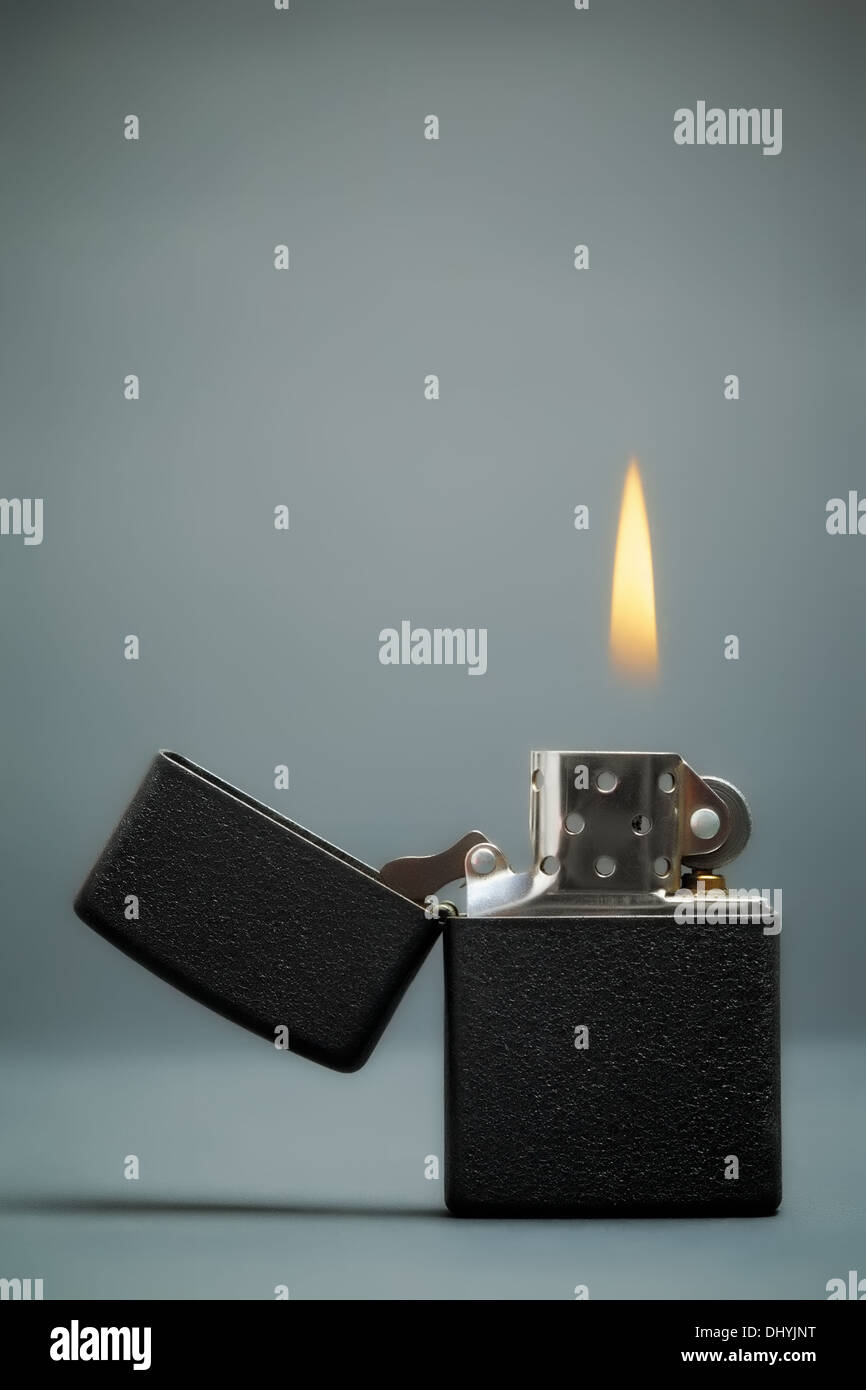 black gasoline lighter with flame on dark background Stock Photo