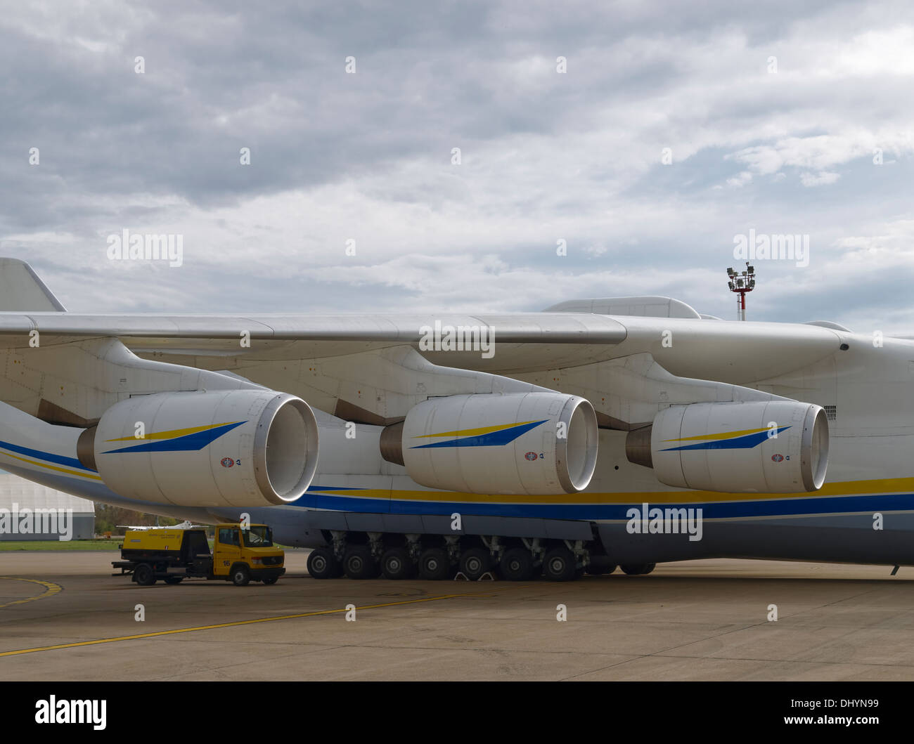 Service truck (power generator) is on the side of the Antonov An-225 airplane with three engines in line for size comparison. Stock Photo