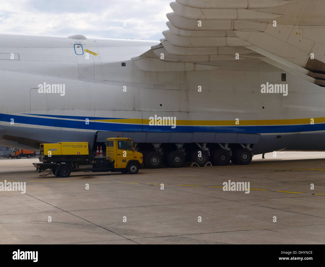 Service truck (power generator) is on the side of the Antonov An-225 airplane for size comparison. Stock Photo