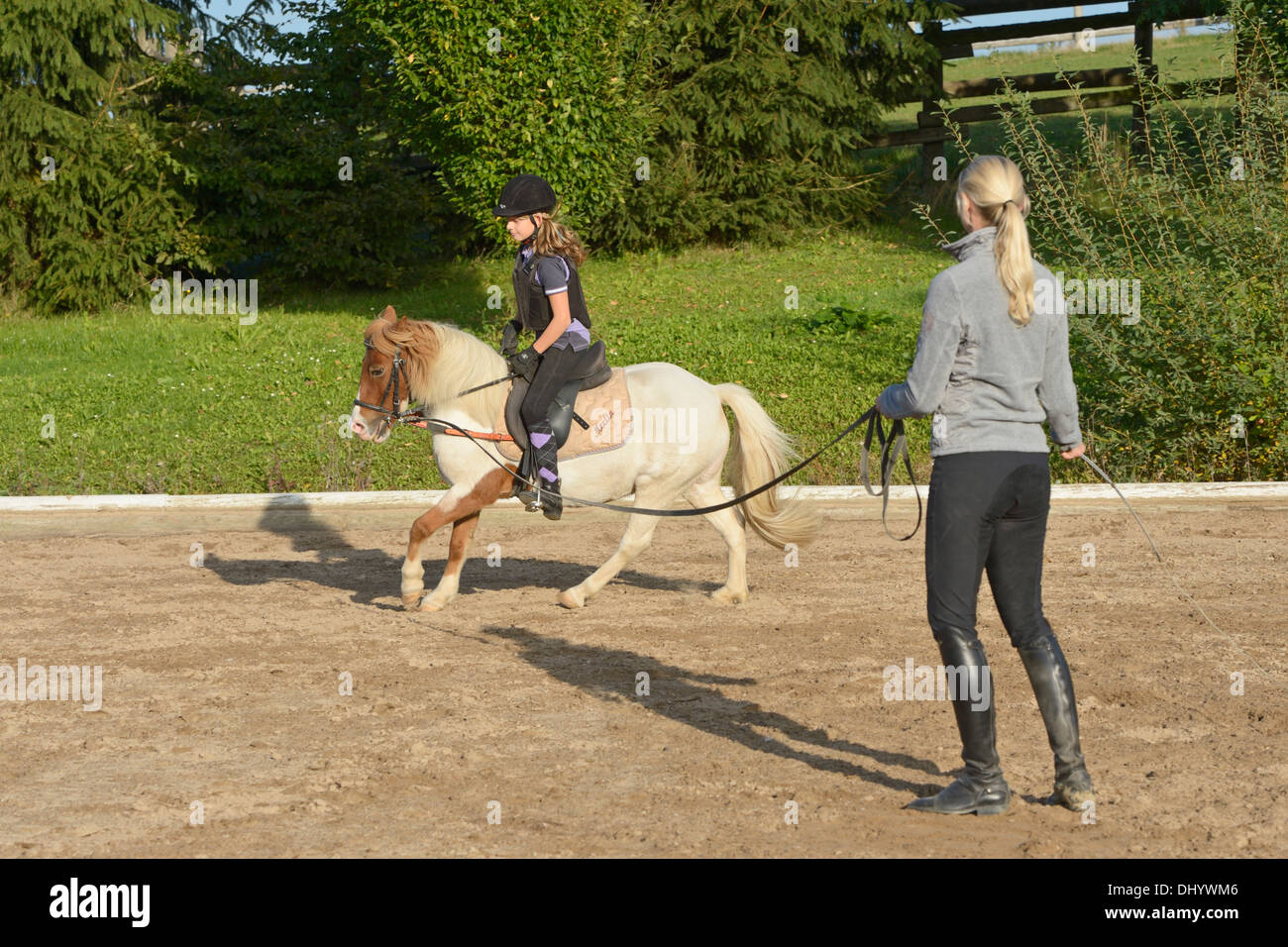 Girl wearing a body protector having a lunge lesson on a pony cantering
