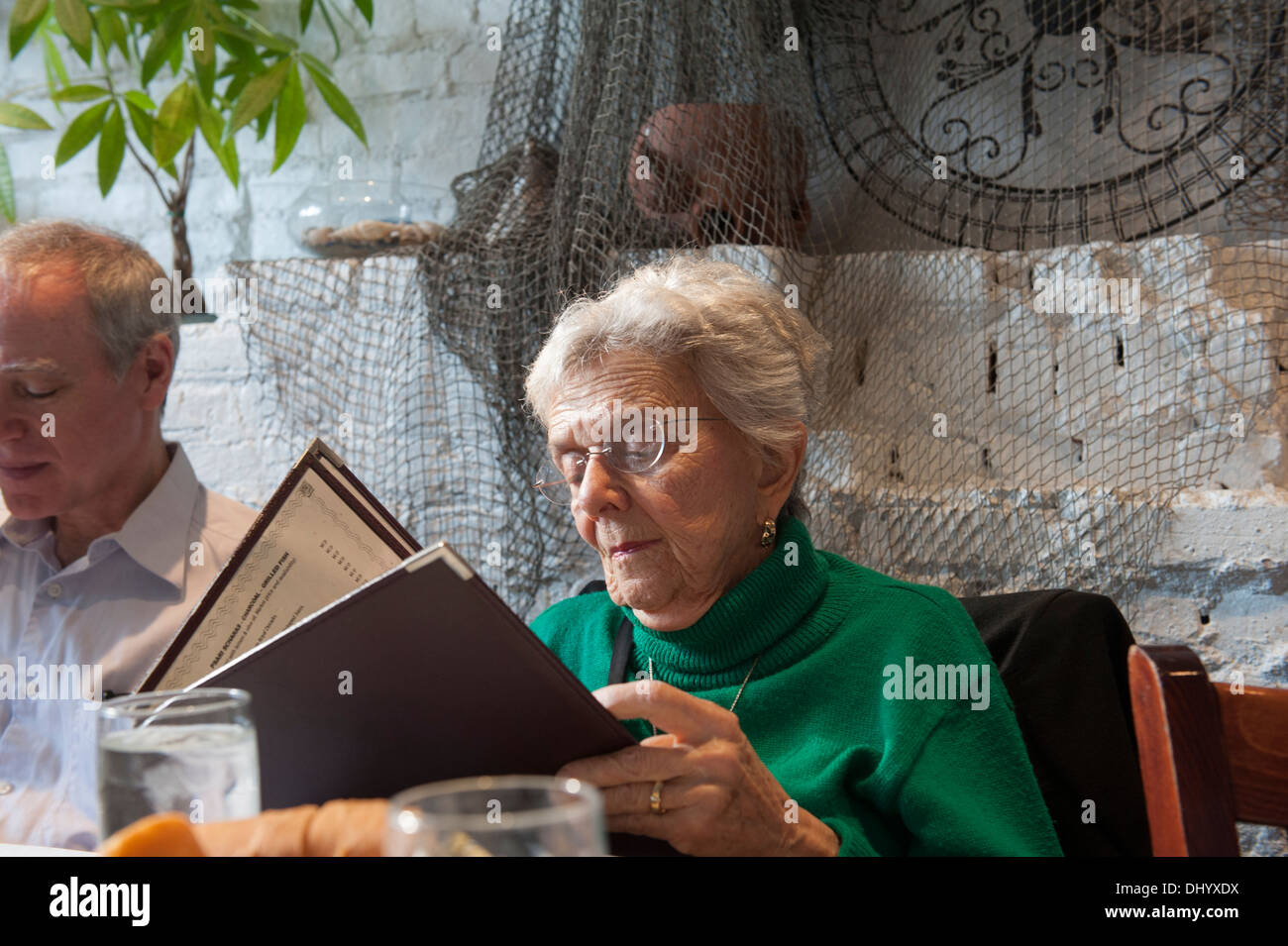 Elderly woman reading a menu in a Greek restaurant in Astoria, Queens, New York City. Stock Photo