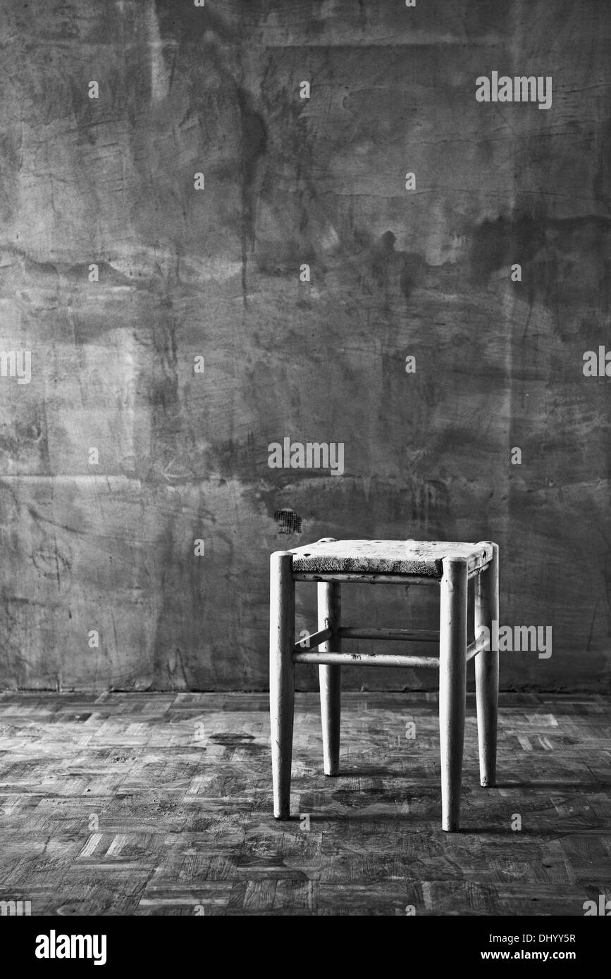 Vintage old wooden chair in grungy interior. Loneliness, estrangement, alienation concept. Stock Photo