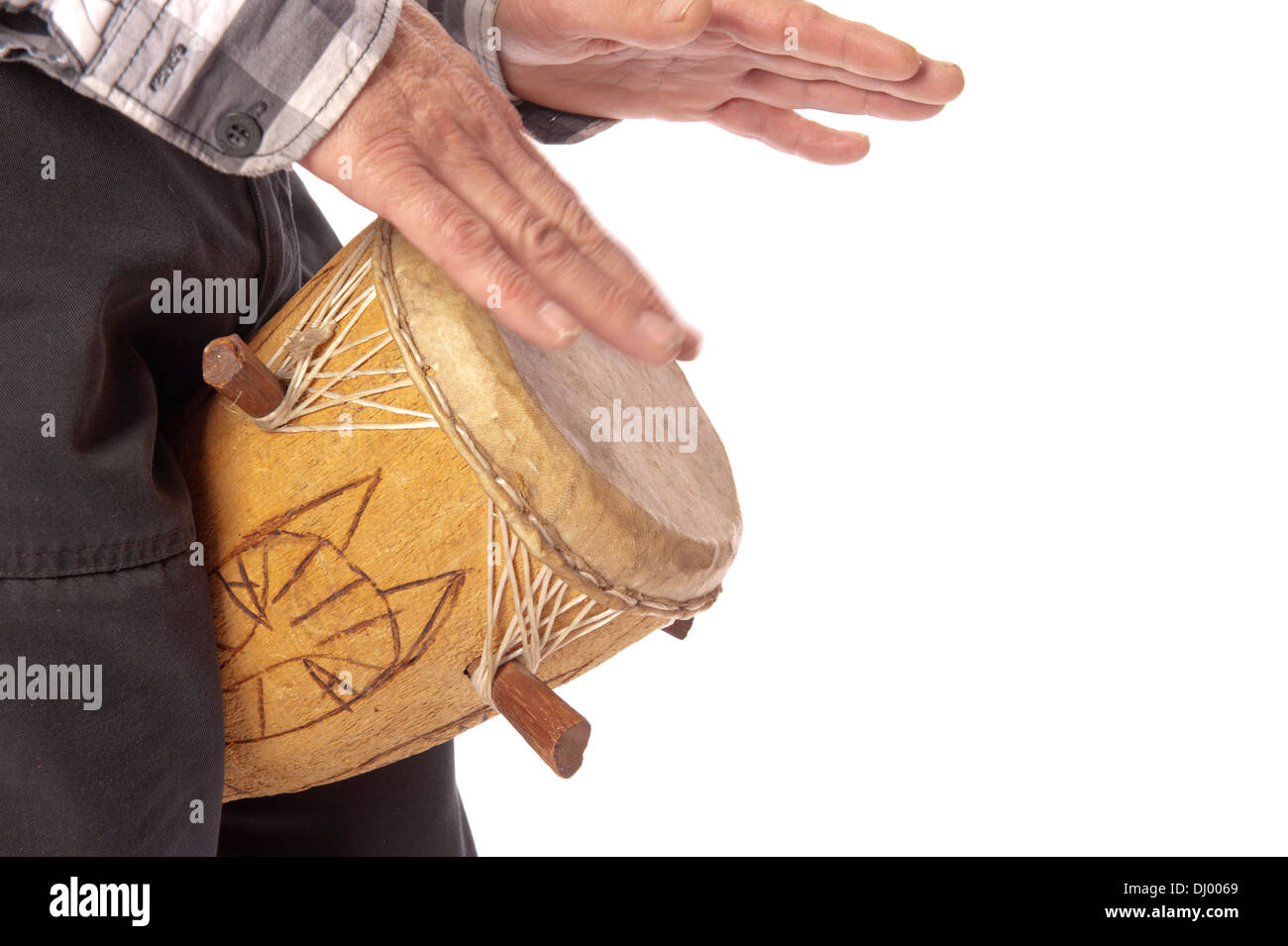 Male figure playing and drumming on African drum between his legs Stock Photo