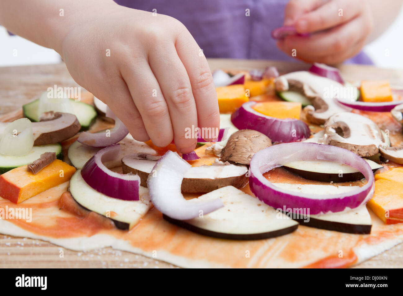 small hands preparing fresh pizza with many vegetables Stock Photo