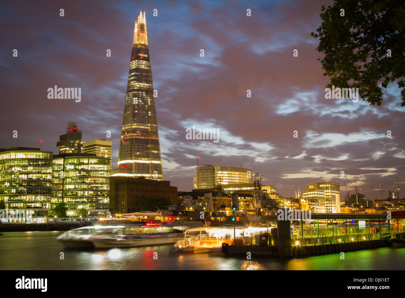 The Shard over the other side of the Thames at night with a catamaran  leaving the jetty Stock Photo