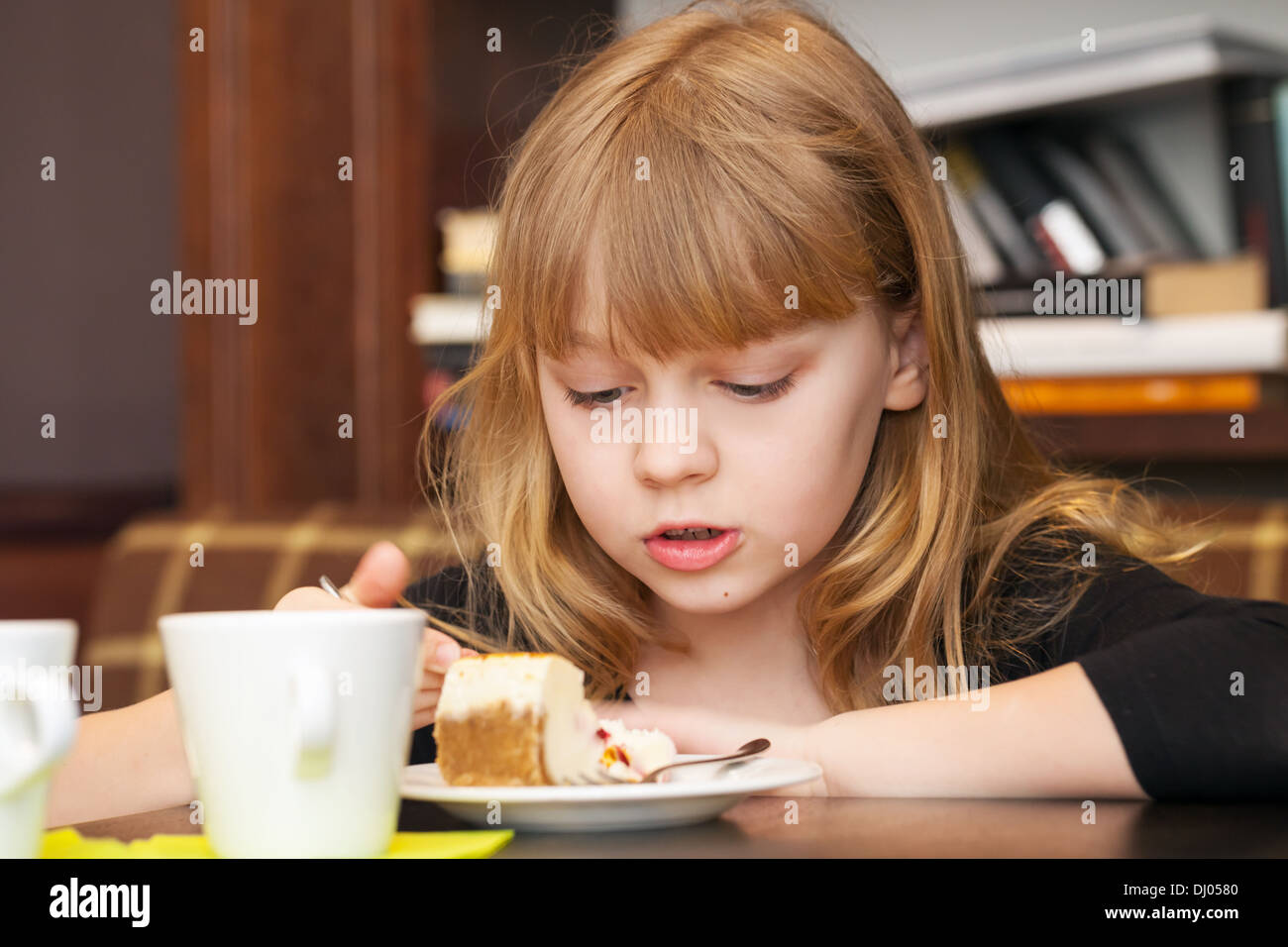 Little blond girl eats cake with tea Stock Photo