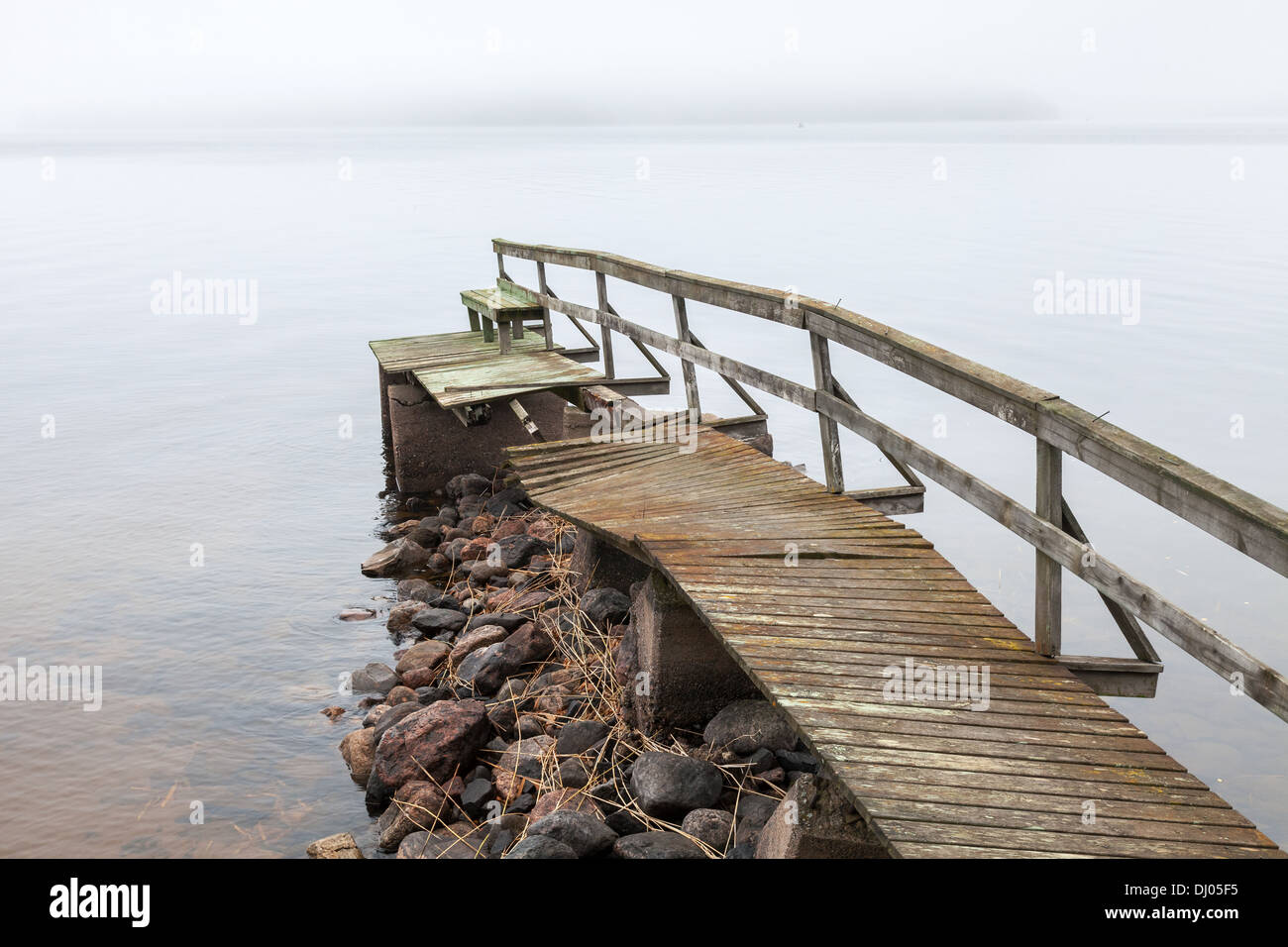 Old ruined wooden pier on the lake in foggy morning Stock Photo